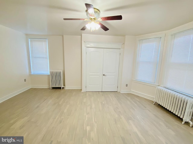 unfurnished bedroom featuring multiple windows, radiator heating unit, light hardwood / wood-style floors, and ceiling fan