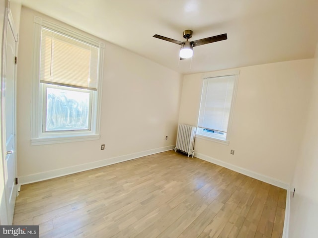 spare room with ceiling fan, light hardwood / wood-style floors, and radiator