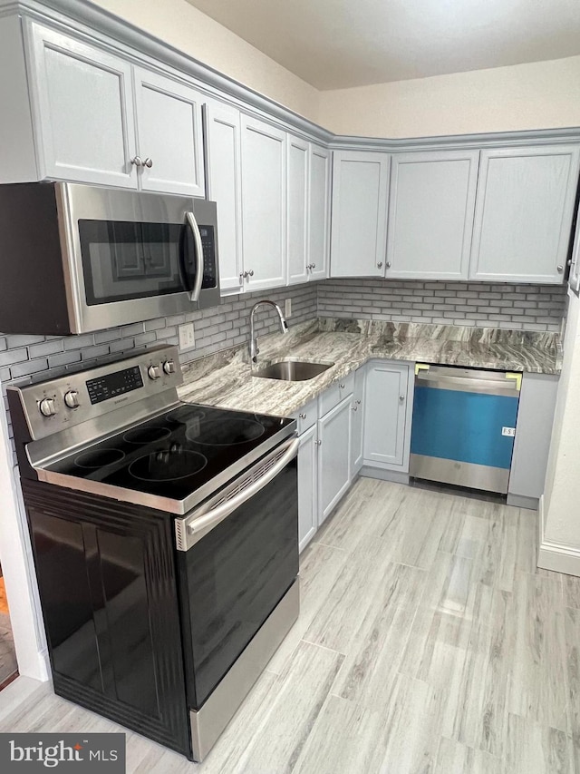 kitchen with decorative backsplash, appliances with stainless steel finishes, light wood-type flooring, and sink