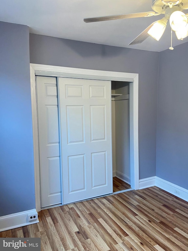 unfurnished bedroom featuring hardwood / wood-style flooring, a closet, and ceiling fan