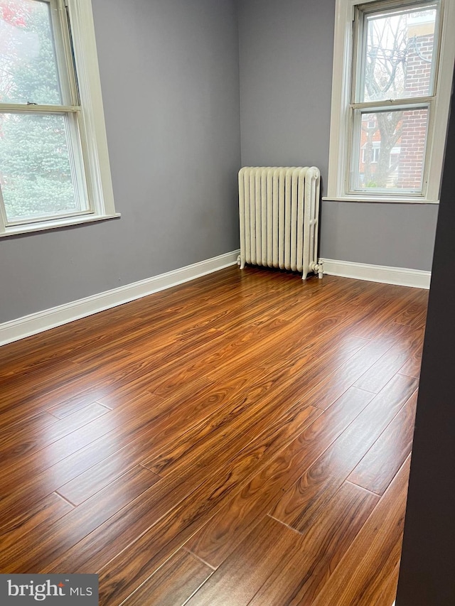 empty room featuring radiator heating unit and hardwood / wood-style flooring