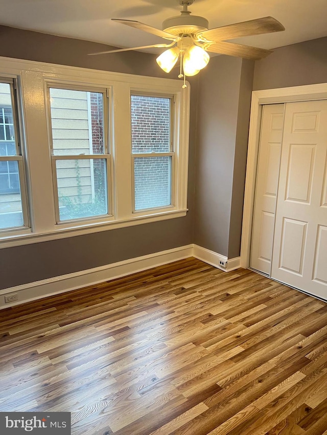 unfurnished bedroom featuring a closet, hardwood / wood-style flooring, and ceiling fan