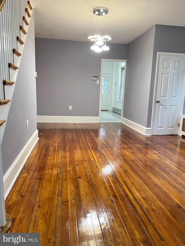 interior space featuring wood-type flooring, an inviting chandelier, and a baseboard heating unit