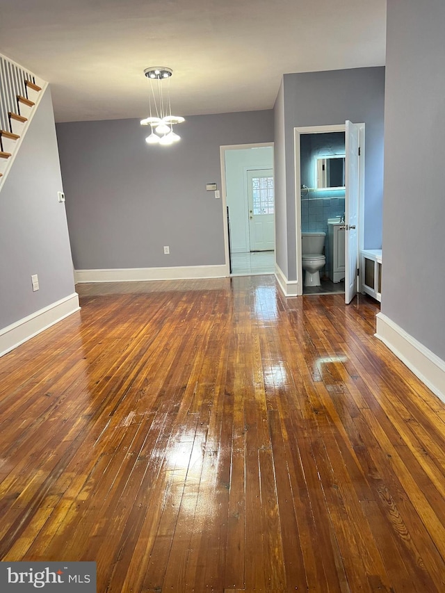 unfurnished living room with dark hardwood / wood-style flooring and a chandelier