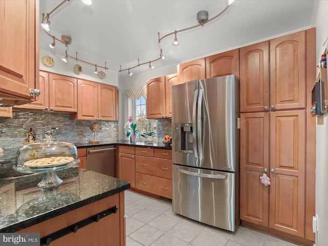 kitchen featuring backsplash, dark stone countertops, light tile patterned floors, and stainless steel appliances