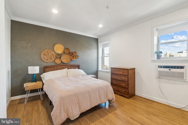 bedroom with a wall mounted air conditioner, light wood-type flooring, and ornamental molding