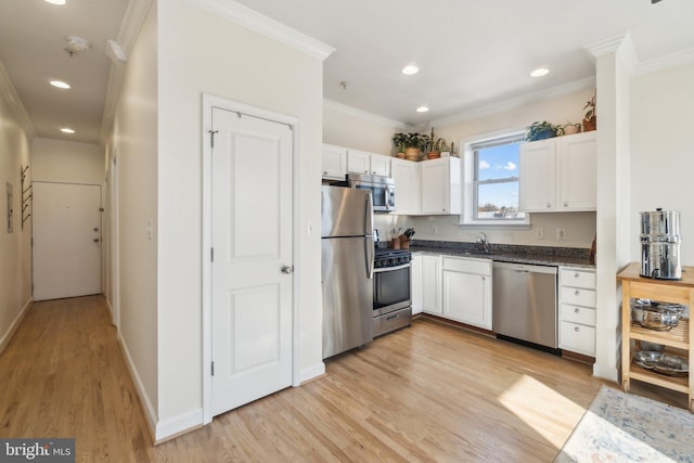 kitchen with appliances with stainless steel finishes, light hardwood / wood-style flooring, white cabinetry, and ornamental molding