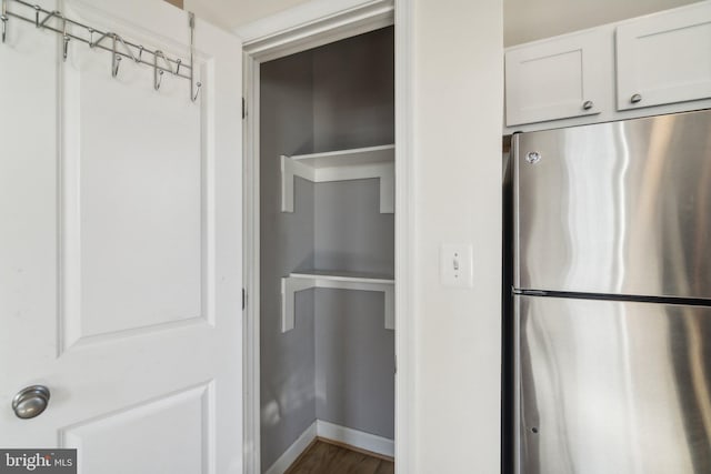 interior space with stainless steel refrigerator, white cabinets, and dark hardwood / wood-style floors