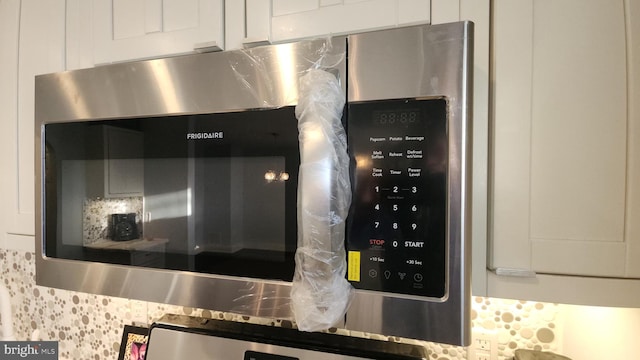 room details featuring stainless steel microwave, wall oven, and white cabinetry