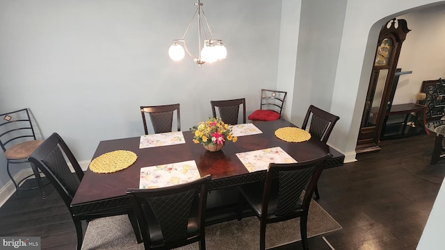 dining room with arched walkways, dark wood-style flooring, an inviting chandelier, and baseboards