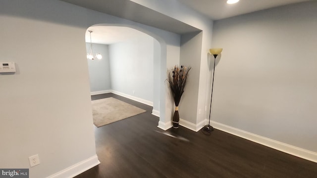 interior space with arched walkways, dark wood-style flooring, and baseboards