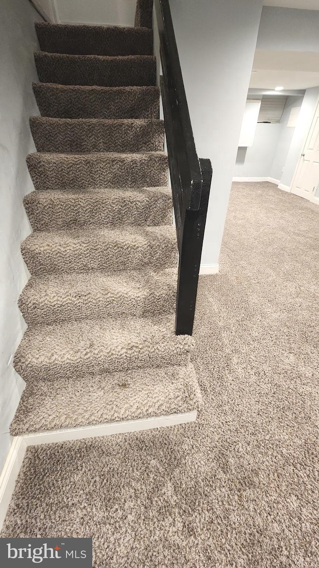 staircase featuring carpet floors and baseboards