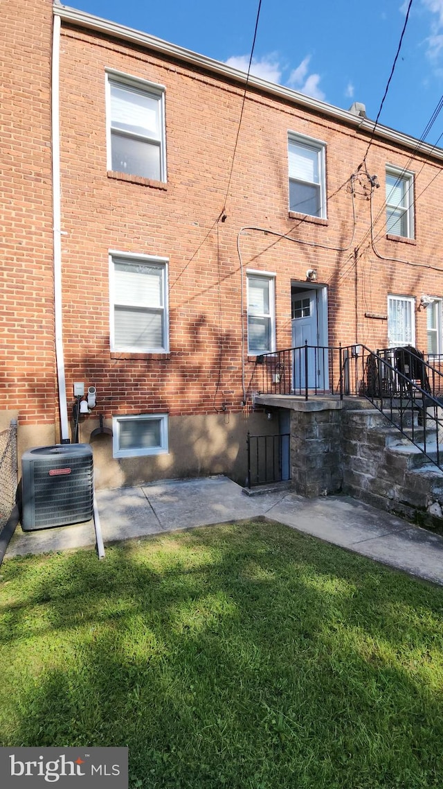 rear view of house with a yard, brick siding, and central air condition unit