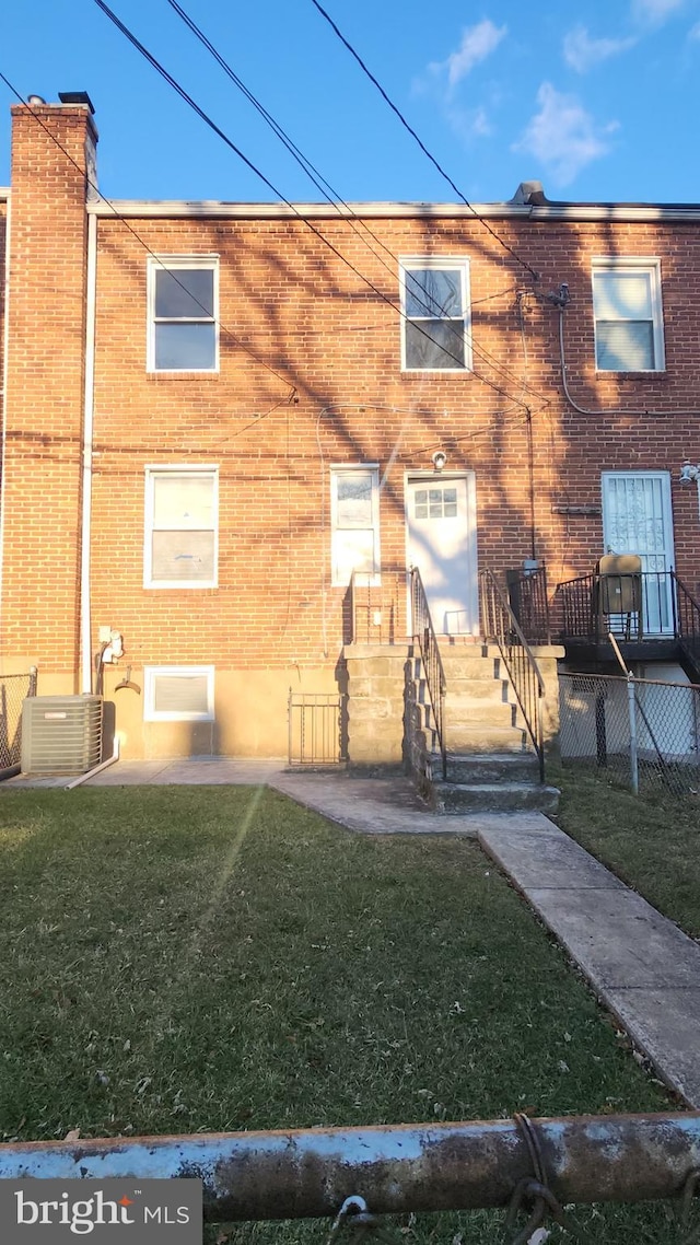 view of front of property with a front lawn, central AC, and brick siding