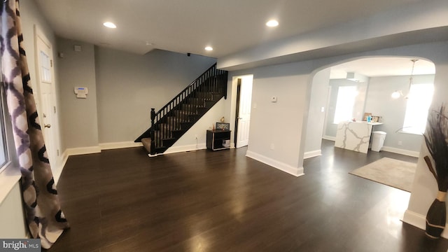 below grade area with baseboards, arched walkways, dark wood-style flooring, and recessed lighting