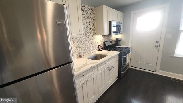 kitchen with light stone counters, stainless steel appliances, a sink, visible vents, and white cabinetry