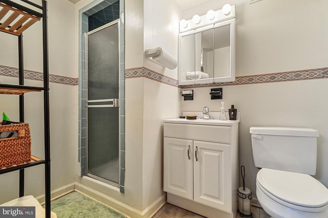 bathroom with tile patterned floors, vanity, a shower with shower door, and toilet