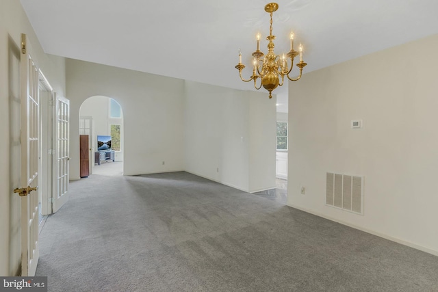 unfurnished room featuring a notable chandelier, a healthy amount of sunlight, and carpet floors