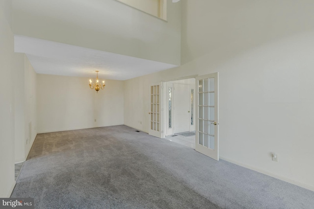 empty room featuring light carpet, french doors, and an inviting chandelier