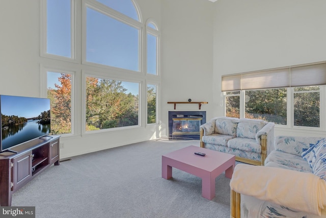 living room with a wealth of natural light, light colored carpet, and a high ceiling