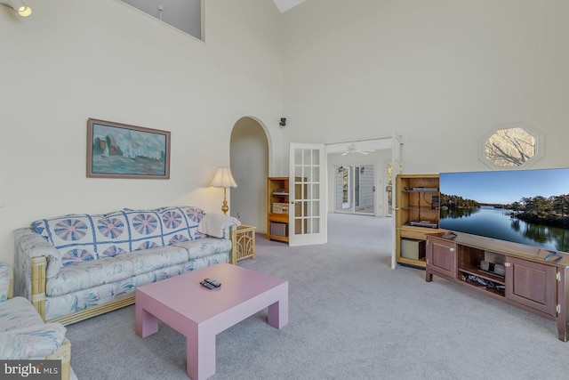 living room featuring light carpet, french doors, ceiling fan, and a high ceiling