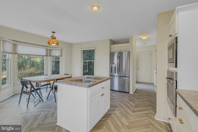 kitchen with white cabinetry, a wealth of natural light, a kitchen island, and appliances with stainless steel finishes