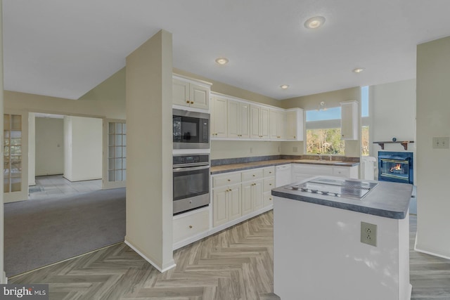 kitchen with a kitchen island, white cabinetry, appliances with stainless steel finishes, and light parquet floors