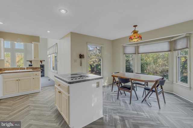 kitchen with a center island, sink, stainless steel cooktop, and a healthy amount of sunlight