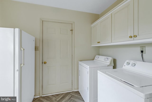 laundry room with cabinets, light parquet flooring, and separate washer and dryer