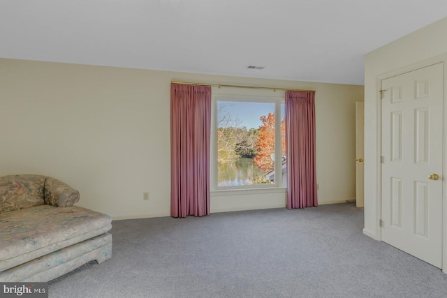 unfurnished room featuring a water view and light carpet