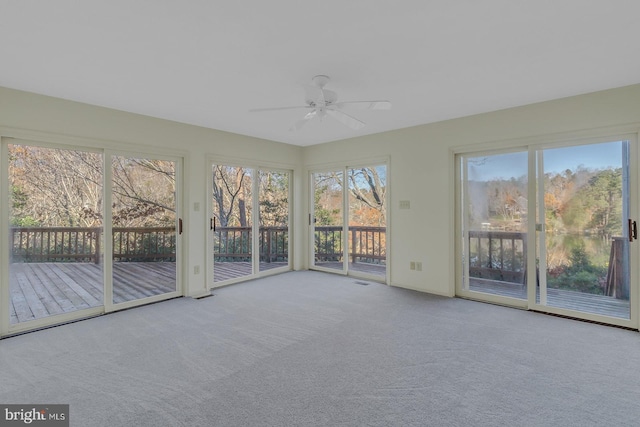 unfurnished sunroom featuring ceiling fan and a wealth of natural light