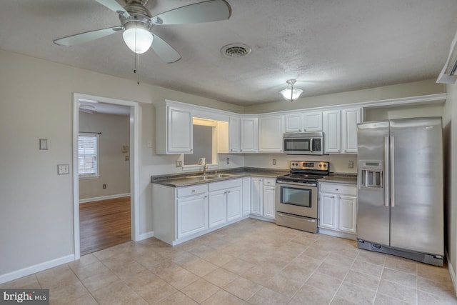 kitchen with white cabinets, appliances with stainless steel finishes, ceiling fan, and sink