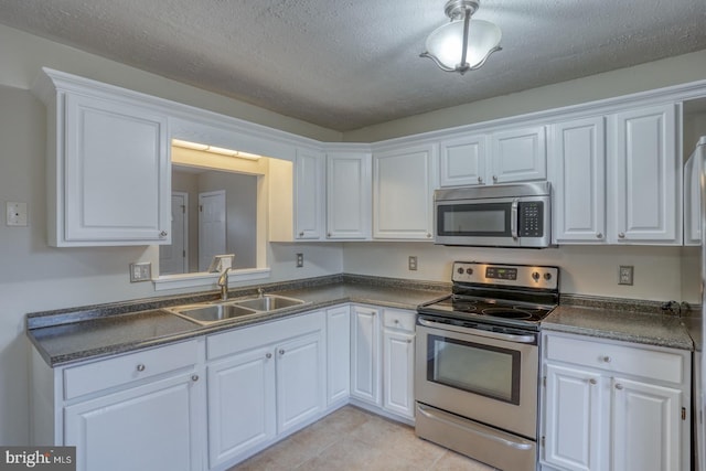 kitchen featuring white cabinetry, sink, a textured ceiling, light tile patterned floors, and appliances with stainless steel finishes