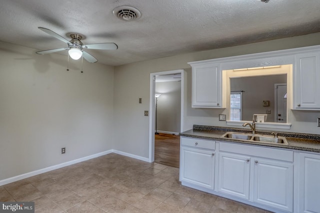 kitchen with ceiling fan, sink, white cabinets, and a textured ceiling