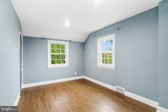 spare room featuring wood-type flooring and lofted ceiling