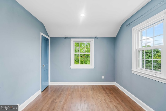 spare room with light wood-type flooring and vaulted ceiling