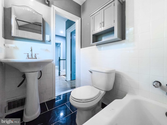 bathroom with a bathing tub, tile patterned flooring, tile walls, and toilet