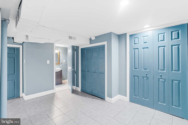 unfurnished bedroom featuring ensuite bath, multiple closets, and light tile patterned flooring