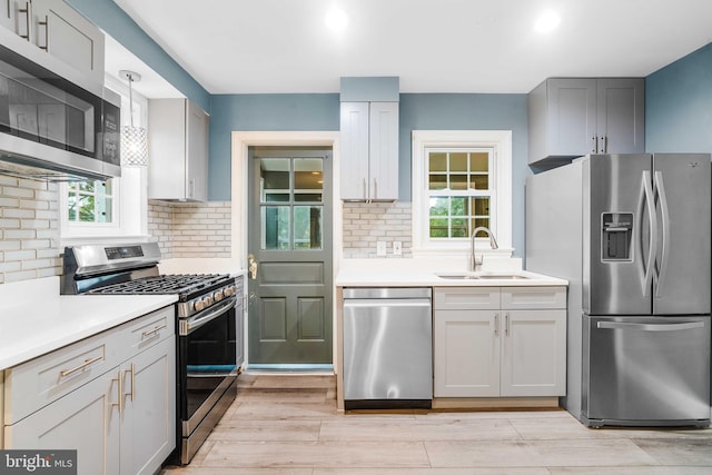 kitchen featuring appliances with stainless steel finishes, tasteful backsplash, gray cabinets, and sink