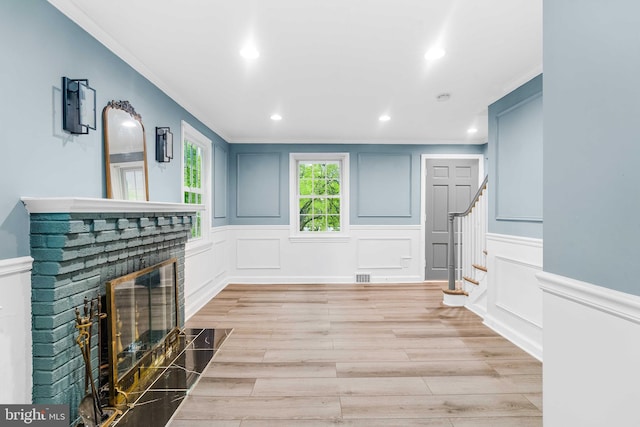 living room featuring a fireplace, light hardwood / wood-style flooring, and ornamental molding