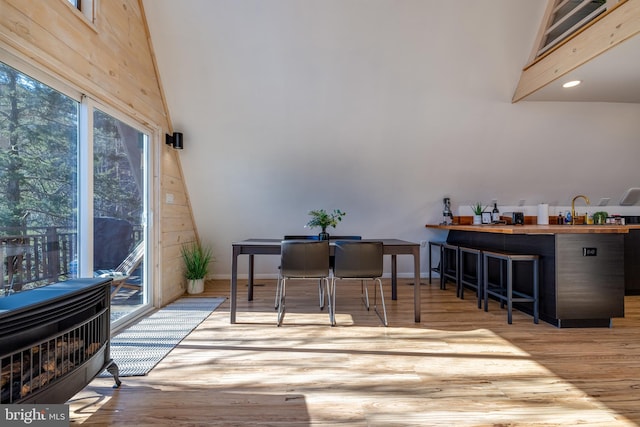 interior space with high vaulted ceiling, light hardwood / wood-style flooring, heating unit, and sink