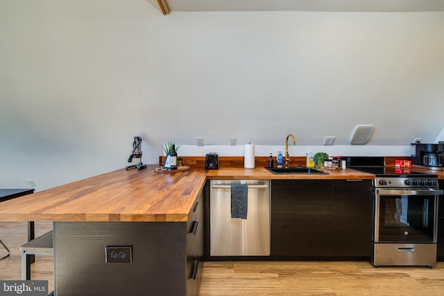 kitchen featuring appliances with stainless steel finishes, light wood-type flooring, butcher block countertops, and sink