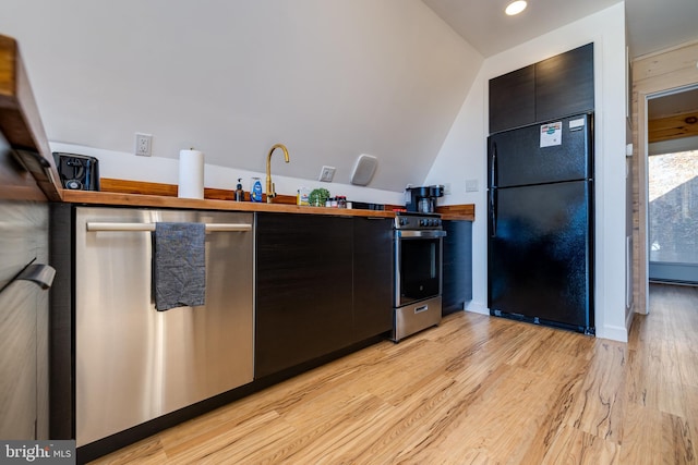 kitchen with light hardwood / wood-style floors, vaulted ceiling, and appliances with stainless steel finishes