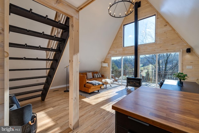 bedroom with multiple windows, wooden walls, high vaulted ceiling, and light wood-type flooring