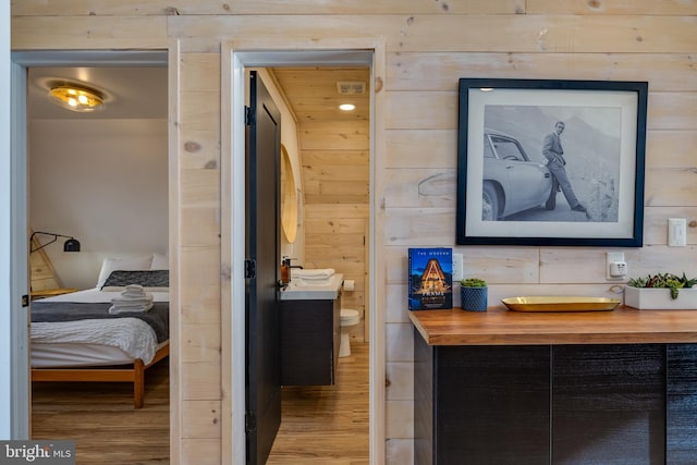 bathroom with wood-type flooring, vanity, toilet, and wood walls