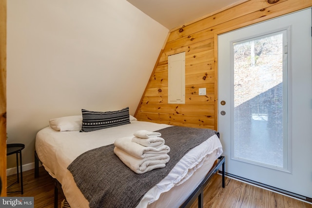 bedroom with hardwood / wood-style flooring, vaulted ceiling, and wood walls