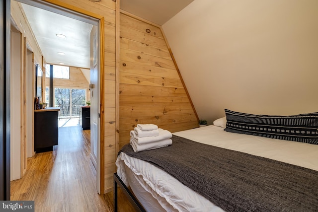 bedroom with hardwood / wood-style flooring and wooden walls