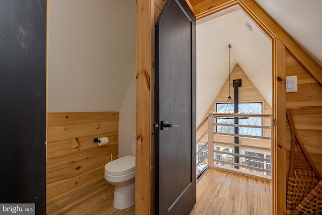 bathroom featuring hardwood / wood-style flooring, toilet, and wooden walls