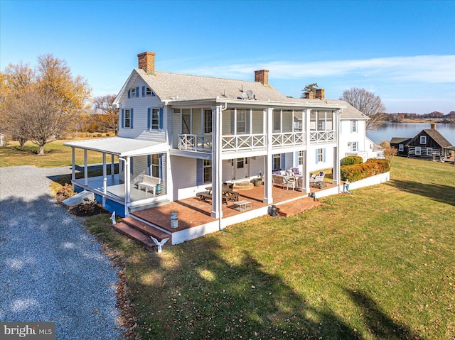 back of house with a lawn, a water view, and a patio