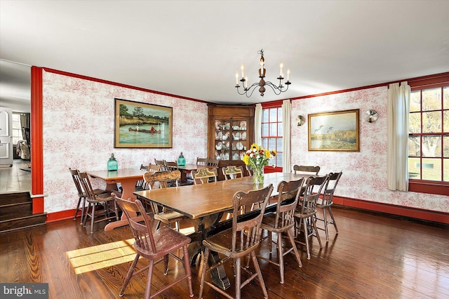 dining room with dark wood-type flooring, a notable chandelier, plenty of natural light, and crown molding